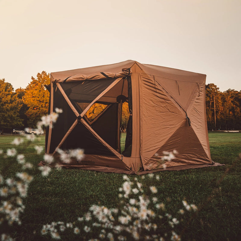 Load image into Gallery viewer, Gazelle Tents G6 Deluxe 6-Sided Portable Gazebo set up in a field at dusk with trees in the background, highlighting spacious design and easy access.
