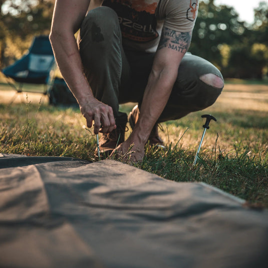 Person setting up a Gazelle Tents T4 Hub Tent Overland Edition at a campsite with another tent in the background.