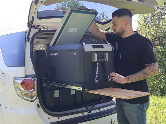 Man using Front Runner 4 Wolf Pack Pro Storage System for vehicle organization with portable Dometic CFX fridge outdoors