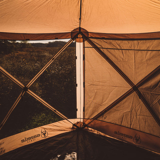 Alt text: "Inside view of a Gazelle Gazebo Screen Tent with Wind Panels set up in a field during sunset."