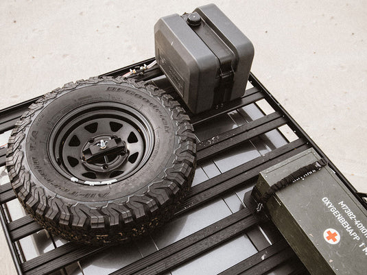 Front Runner Spare Wheel Clamp securely holding a black all-terrain tire on a vehicle roof rack