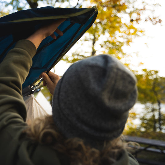 Person setting up a Territory Tents Jet Set 4 Hub Tent in an autumn forest setting.