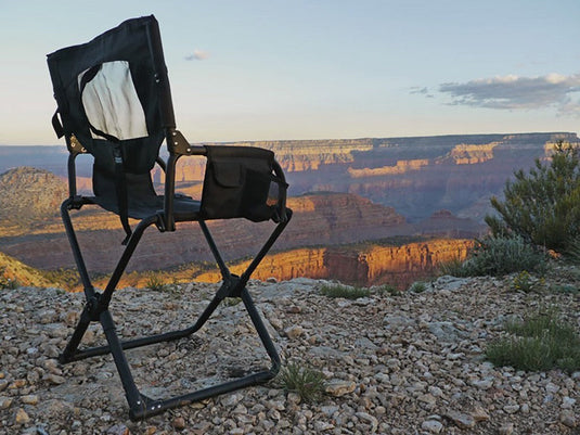 Front Runner Expander Camping Chair set up on rocky ground with a scenic canyon backdrop during sunset.