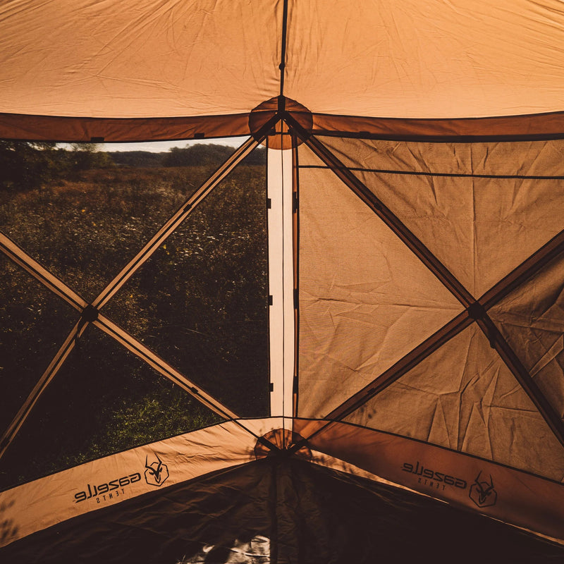 Load image into Gallery viewer, Gazelle Tents G6 6-Sided Portable Gazebo set up in a field at dusk, showcasing the wind panels and durable frame.
