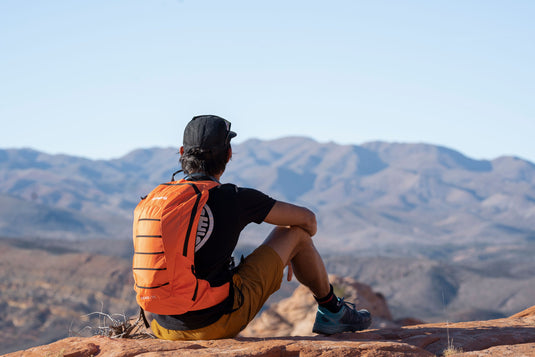 Hiker resting on mountain trail with Klymit Echo 12L Hydration Pack