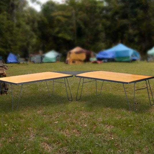 inchOverland Vehicle Systems portable camping tables with wood base set up outdoors near tents at a campsiteinch