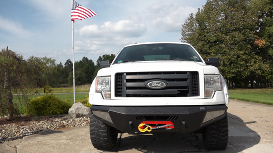 alt="Fishbone Offroad 2009-2014 F-150 Pelican Front Bumper on white Ford truck with American flag in background"