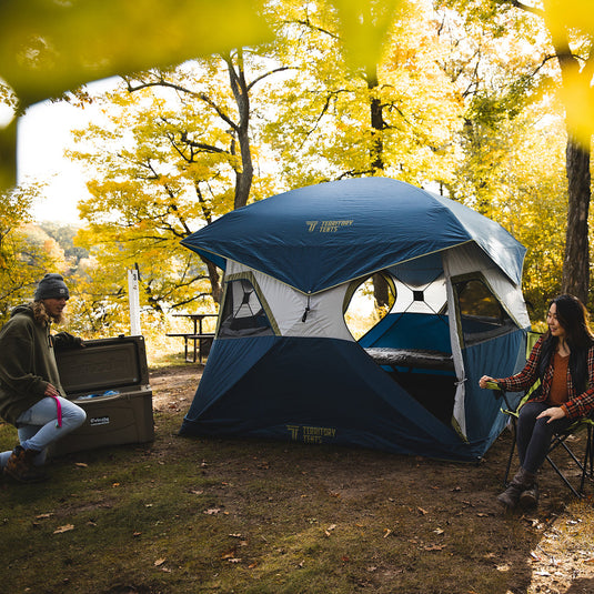 "Campers enjoying outdoor camping with Territory Tents Jet Set 4 Hub Tent in a forest setting during autumn"