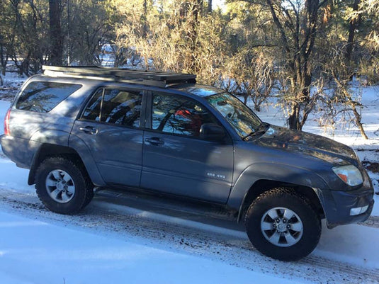 Toyota 4Runner with Front Runner Slimline II Roof Rack Kit installed, parked in snow-covered woodland area.