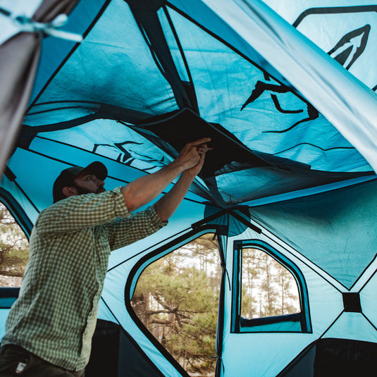 Man setting up Gazelle T3X Overland Edition Tent in the forest.
