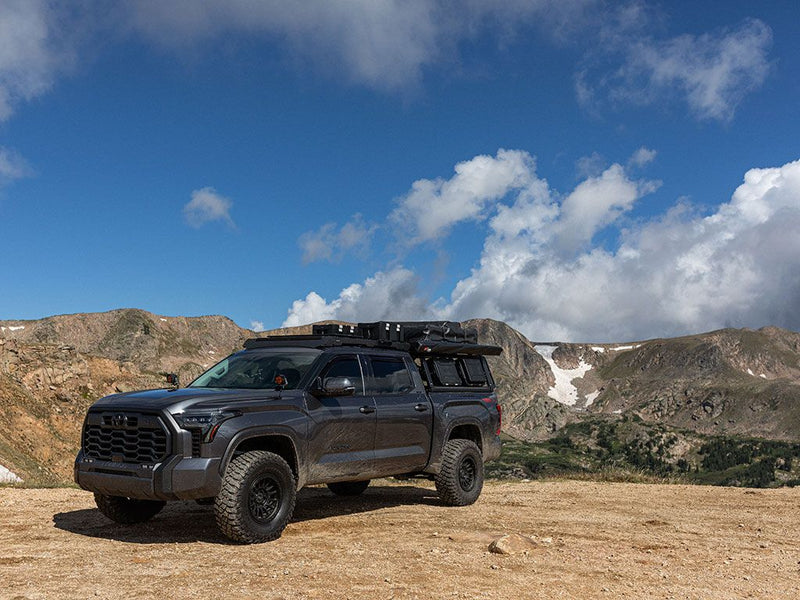 Load image into Gallery viewer, 2022 Toyota Tundra CrewMax with Front Runner Pro Bed Rack Kit against mountainous backdrop.
